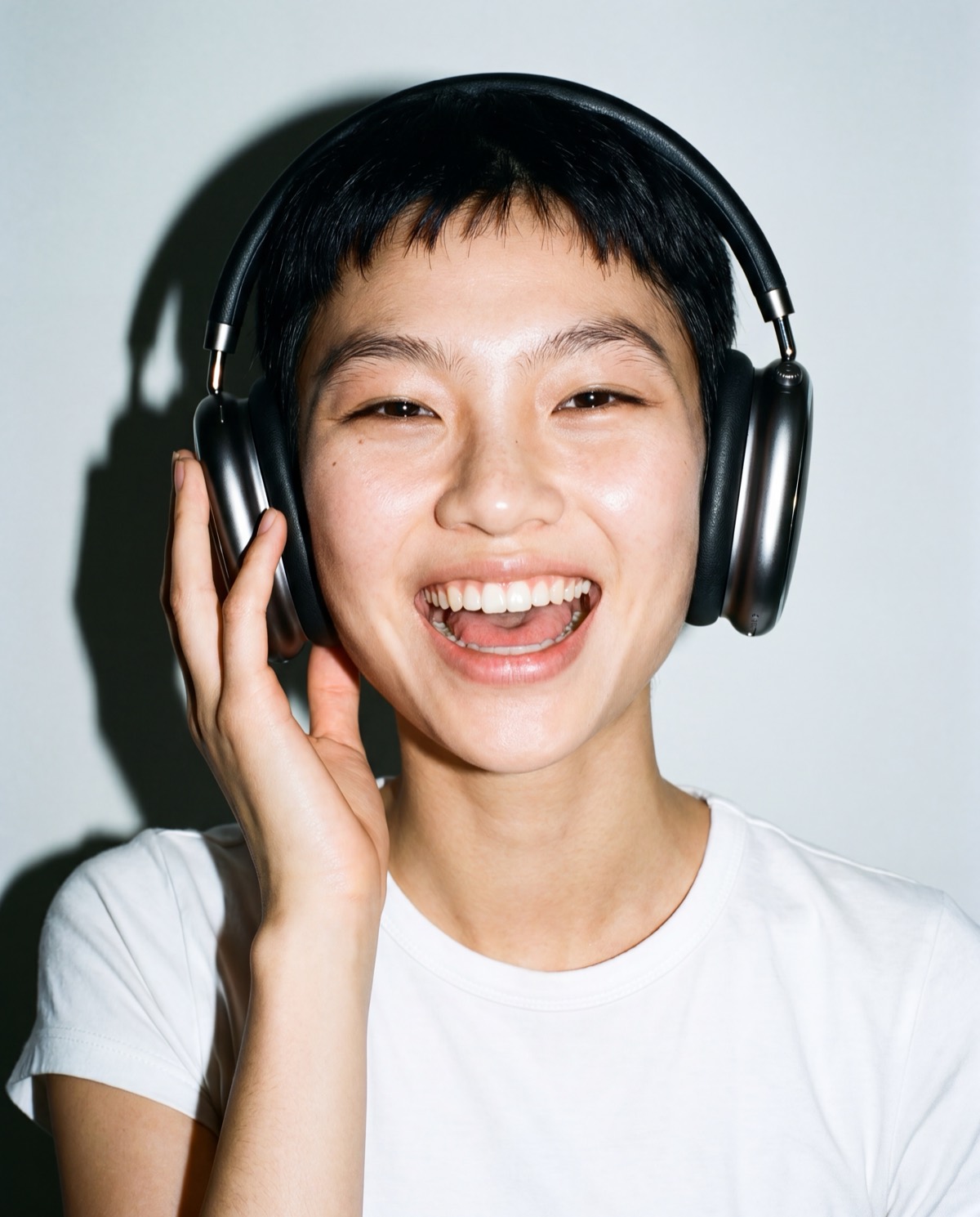 Laughing model wearing Sounds over-ear headphones, shot with hard flash