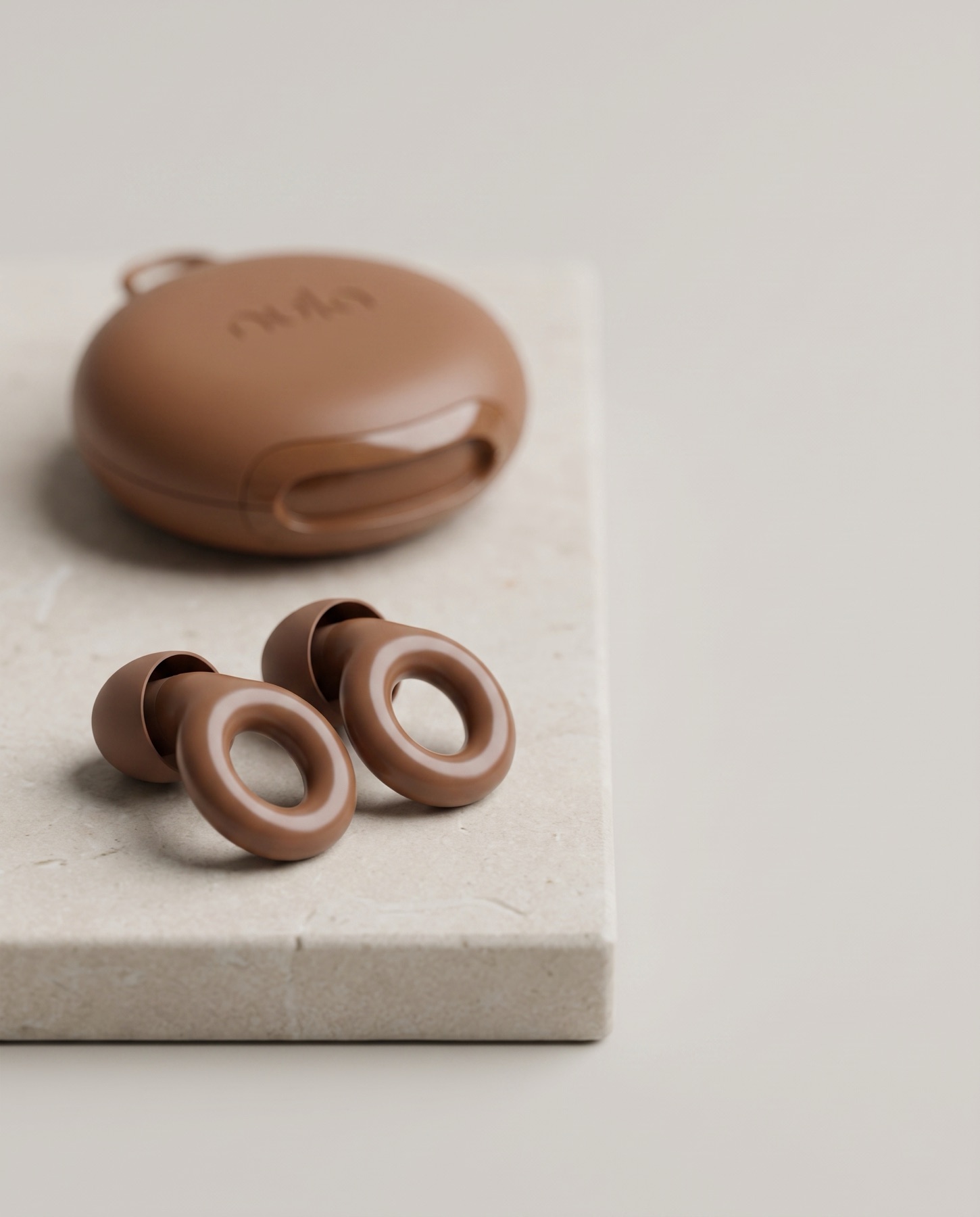 Brown Nula earplugs and their case arranged on a soft neutral surface